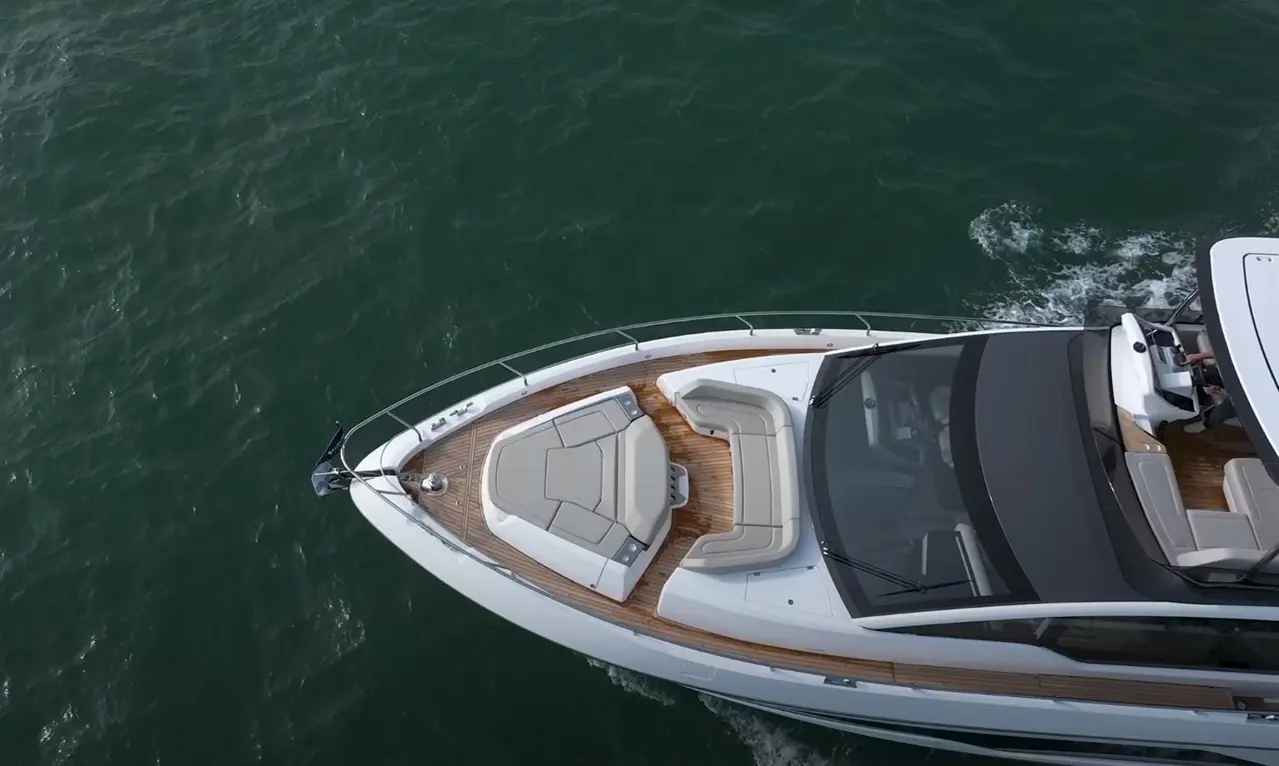 Luxury motorboat with seating area glides over green water, showcasing modern design and craftsmanship.